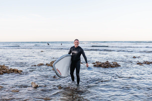 Instructor guiding a young surfer through paddling techniques in calm waters.