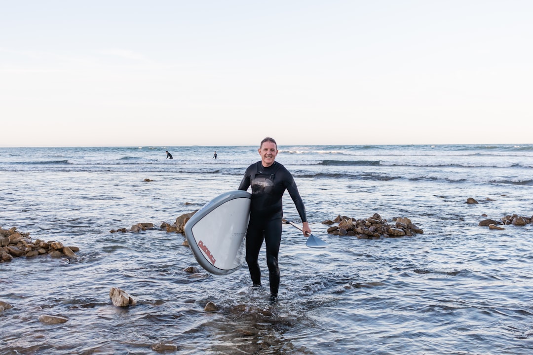 man in black long sleeve shirt and black pants sitting on white and black surfboard on on on on on