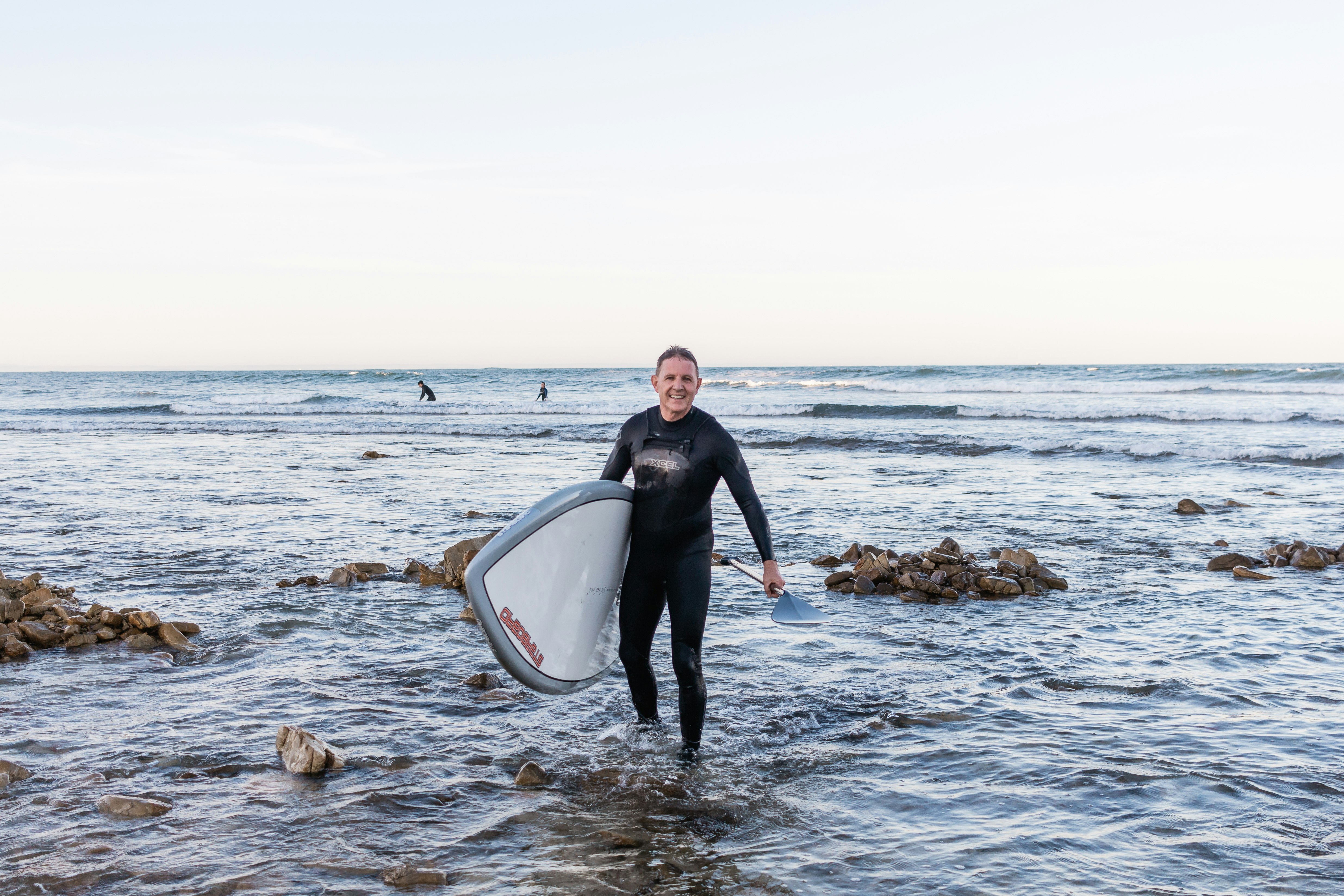 man in black long sleeve shirt and black pants sitting on white and black surfboard on on on on on