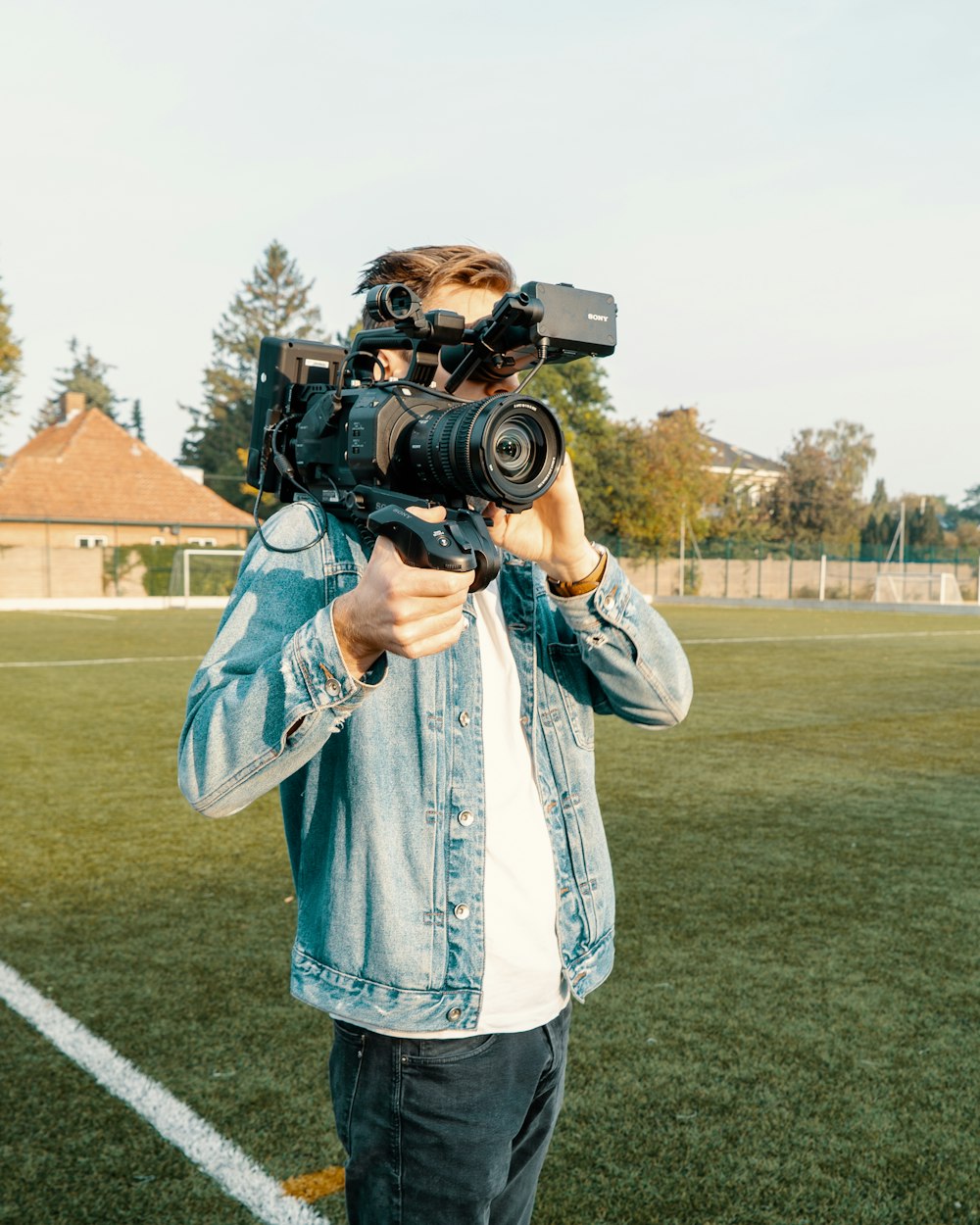 homem na camisa social xadrez branca e azul segurando a câmera dslr preta