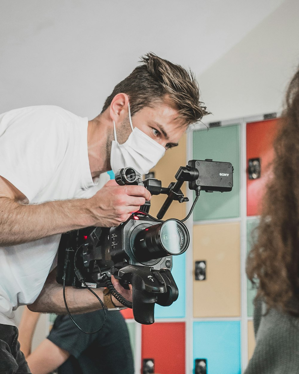 man in white t-shirt holding black dslr camera