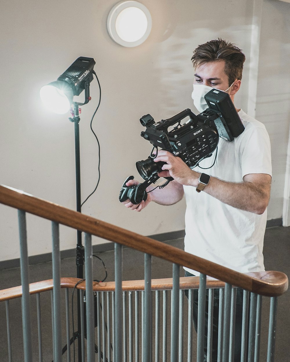 man in white crew neck t-shirt holding black dslr camera