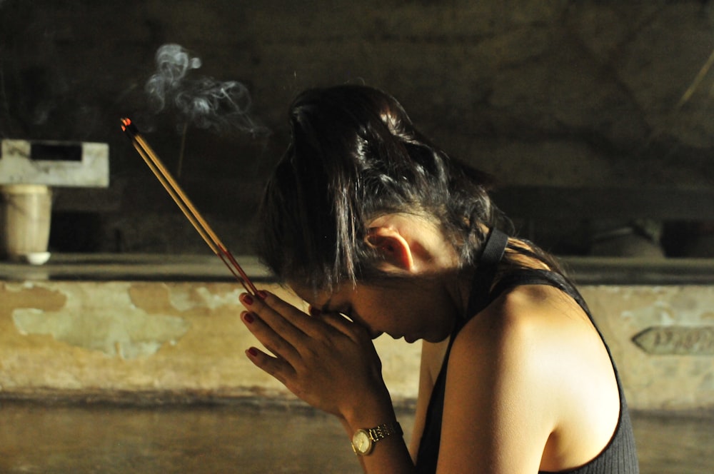 donna in canotta nera che tiene il bastone di sigaretta