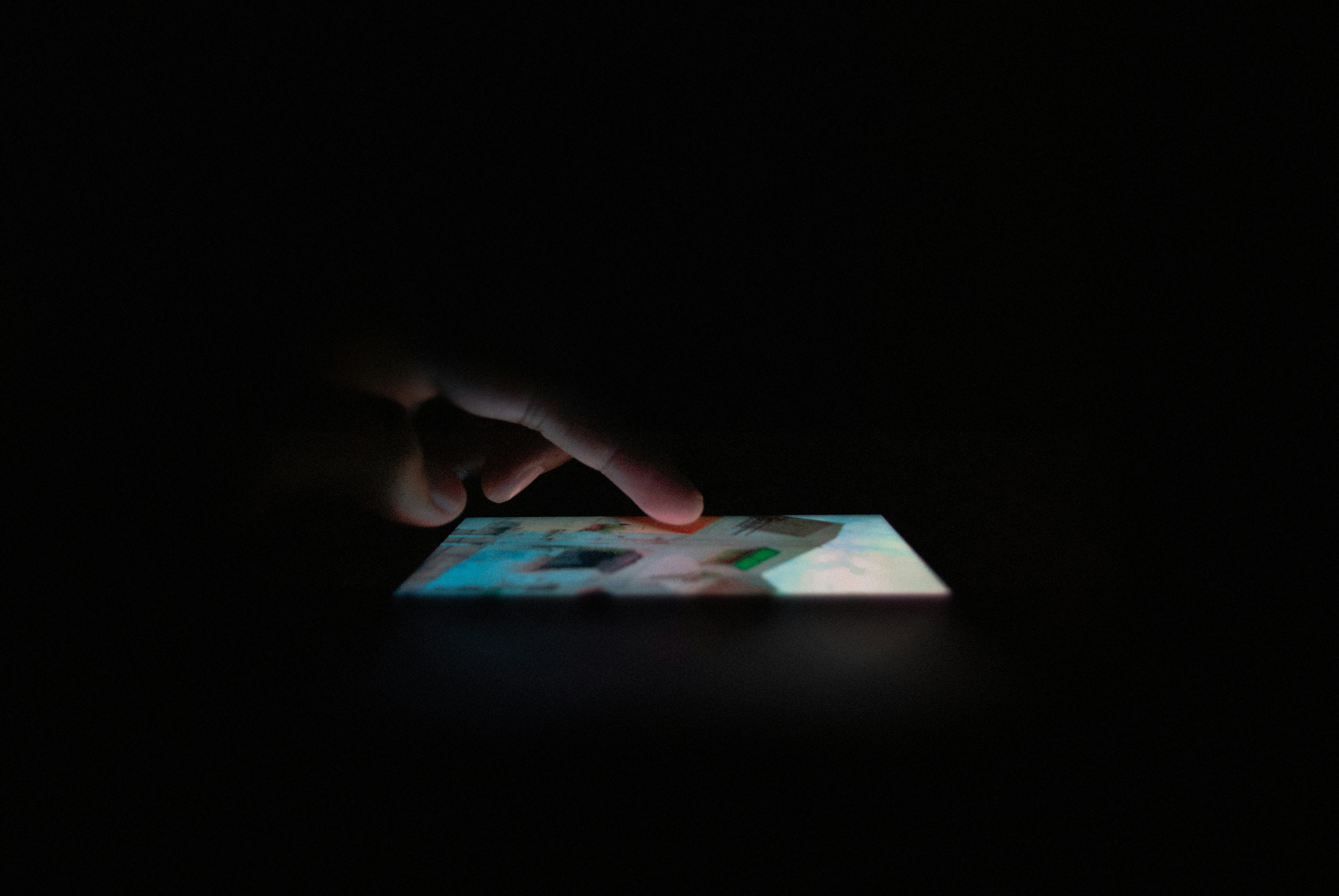 emotional person looking at glowing smartphone screen in dark room