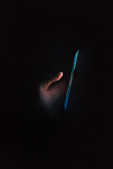 A close-up of hands typing on a phone with a chat interface open, glowing softly in the evening light.