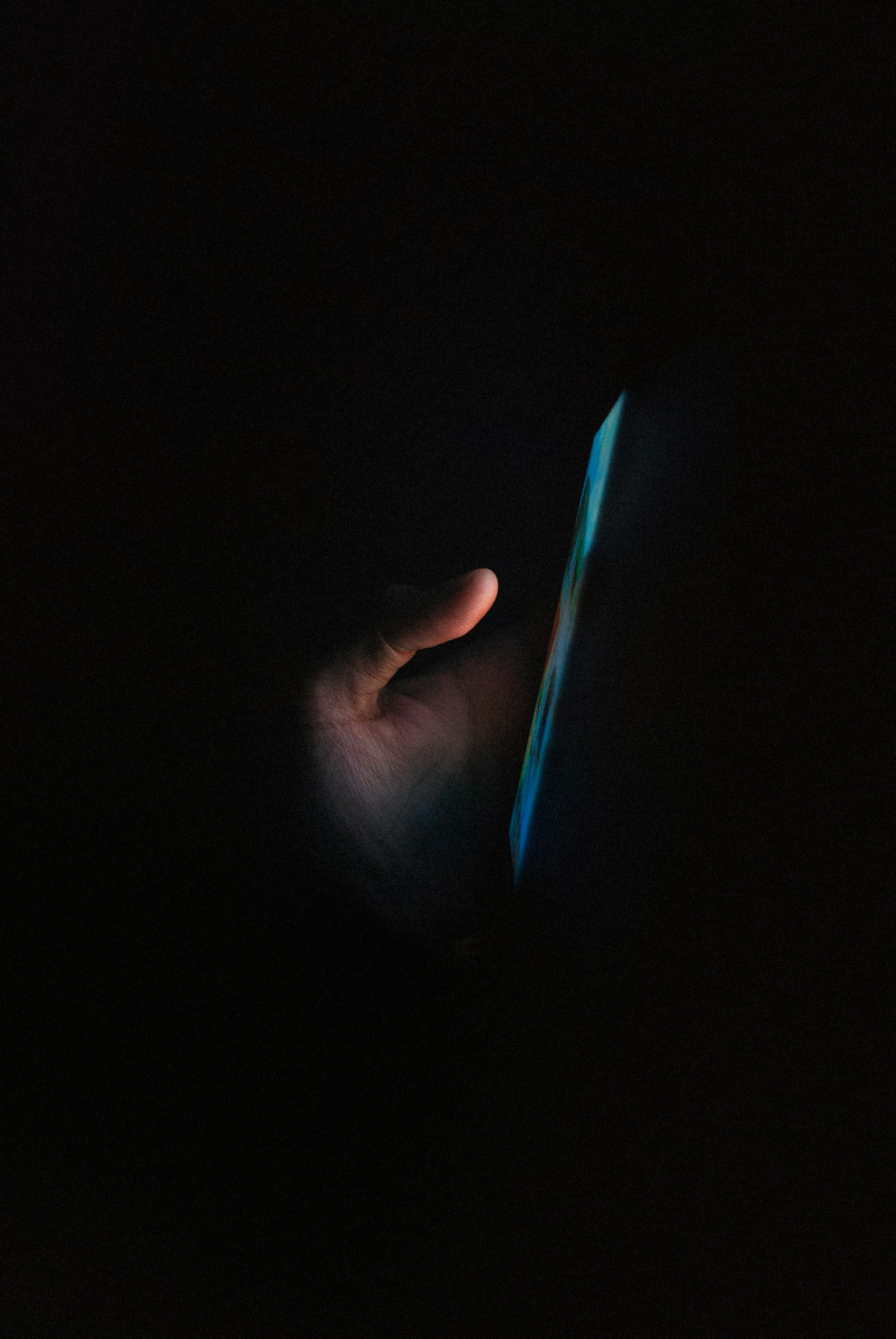 Finger tapping on a glowing smartphone screen in the dark