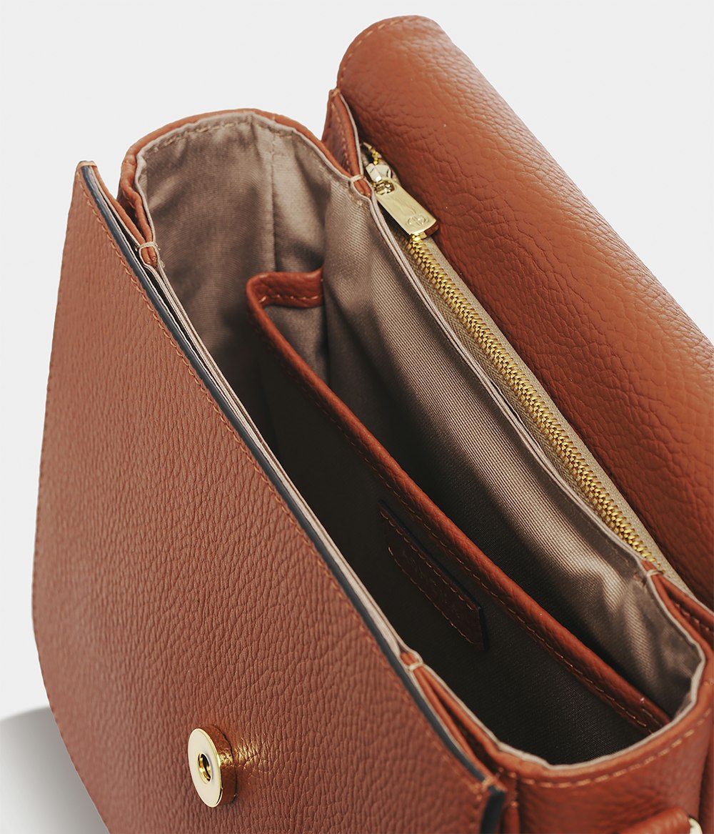 brown leather sling bag on white table