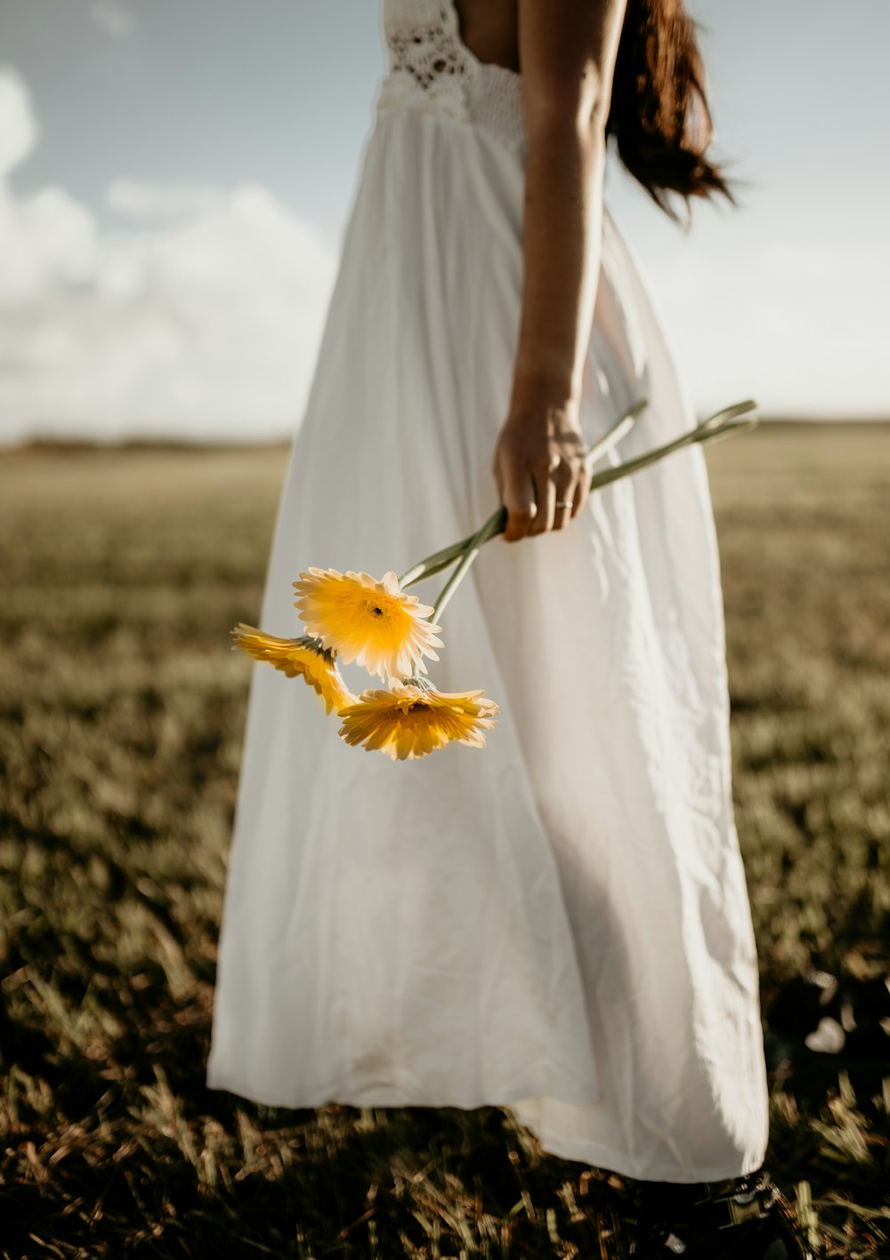 woman in white dress holding yellow flower