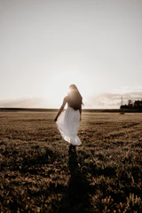 Peaceful scene of a woman walking outdoors at sunrise, embodying calm and wellness.