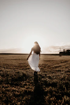 Peaceful scene of a woman walking outdoors at sunrise, embodying calm and wellness.