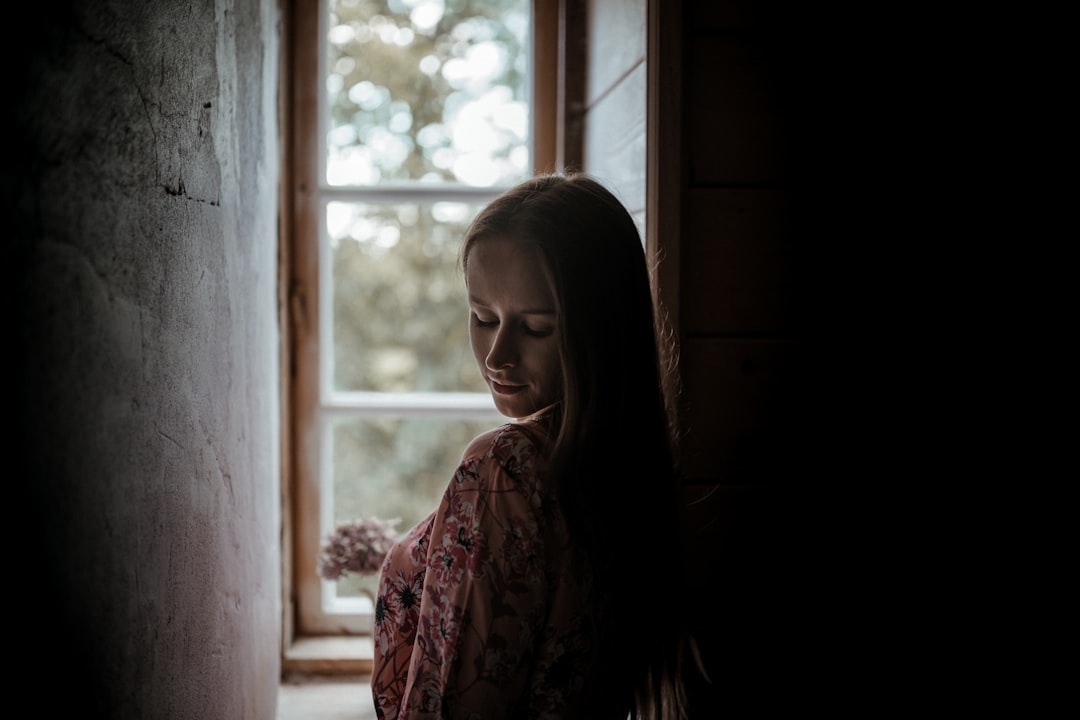 woman in red and white floral dress standing beside window