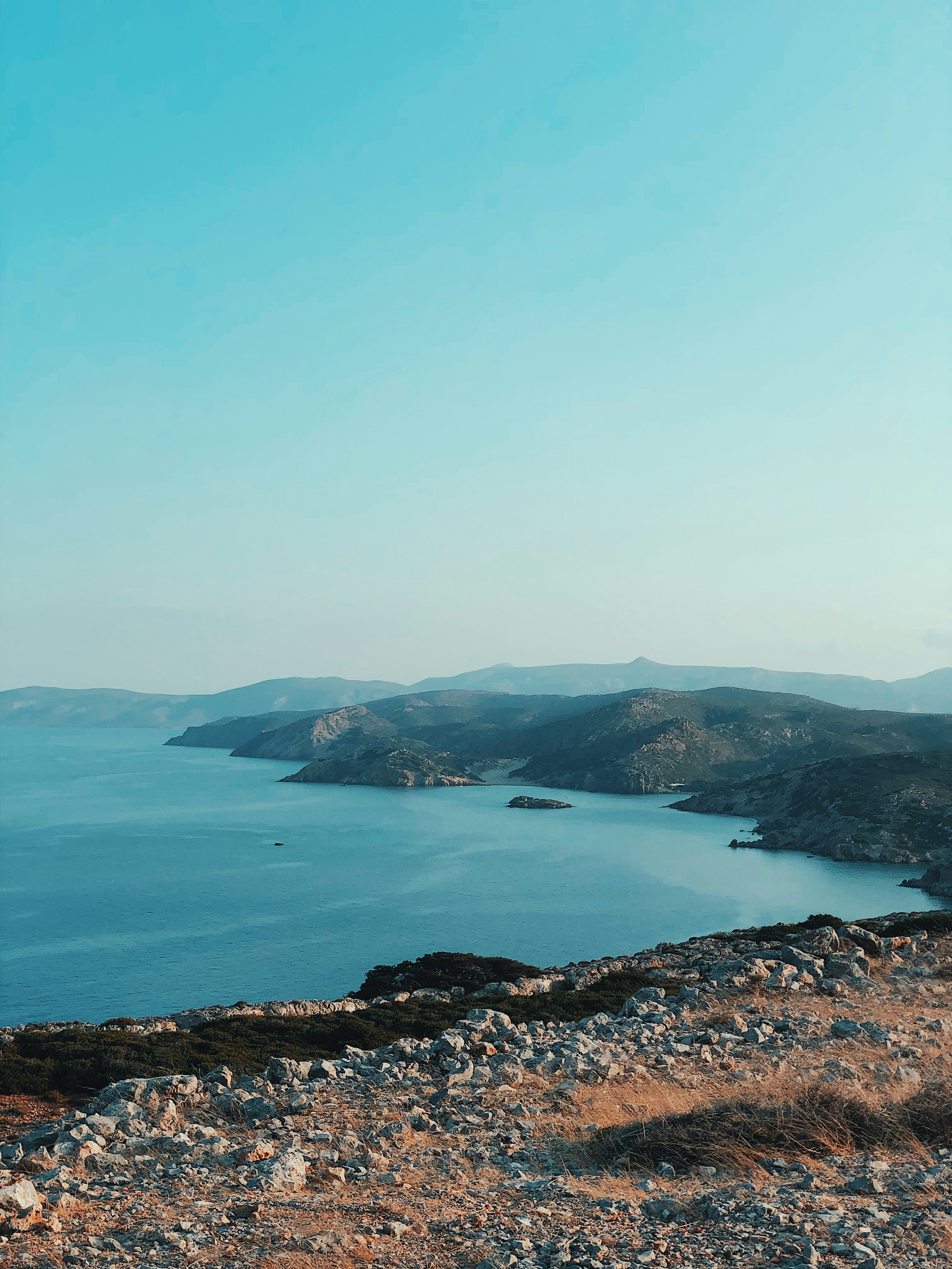 green mountain beside blue sea under blue sky during daytime