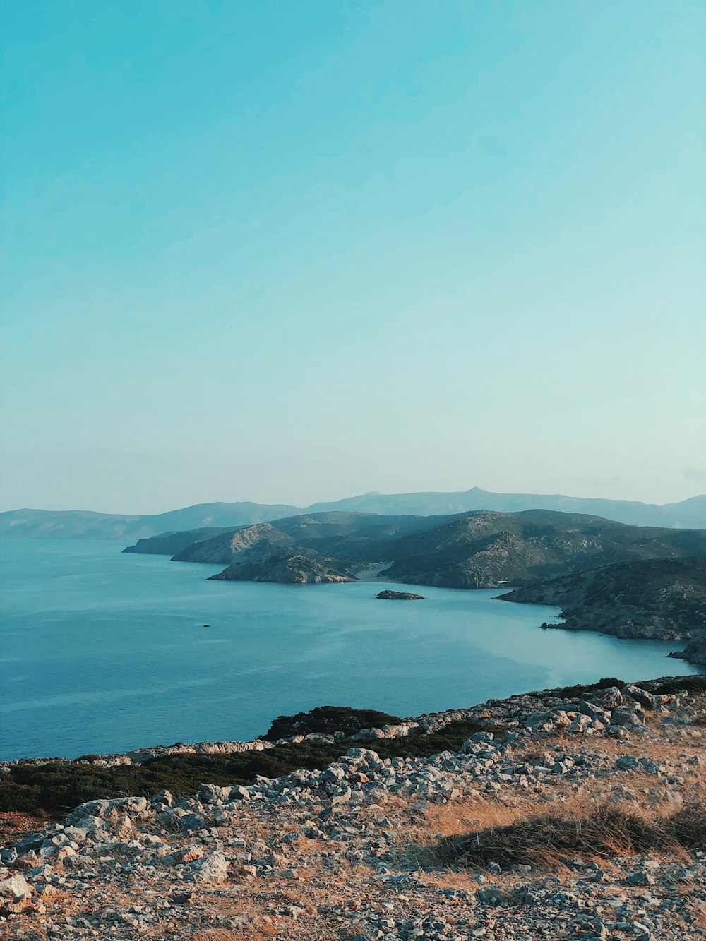 green mountain beside blue sea under blue sky during daytime