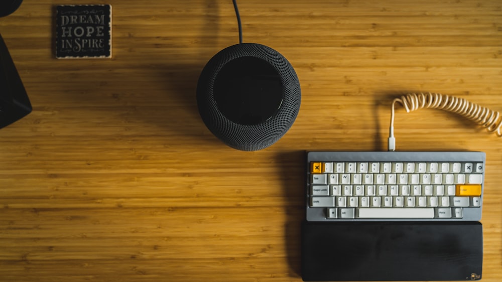 Altavoz portátil negro junto al teclado de computadora en blanco y negro