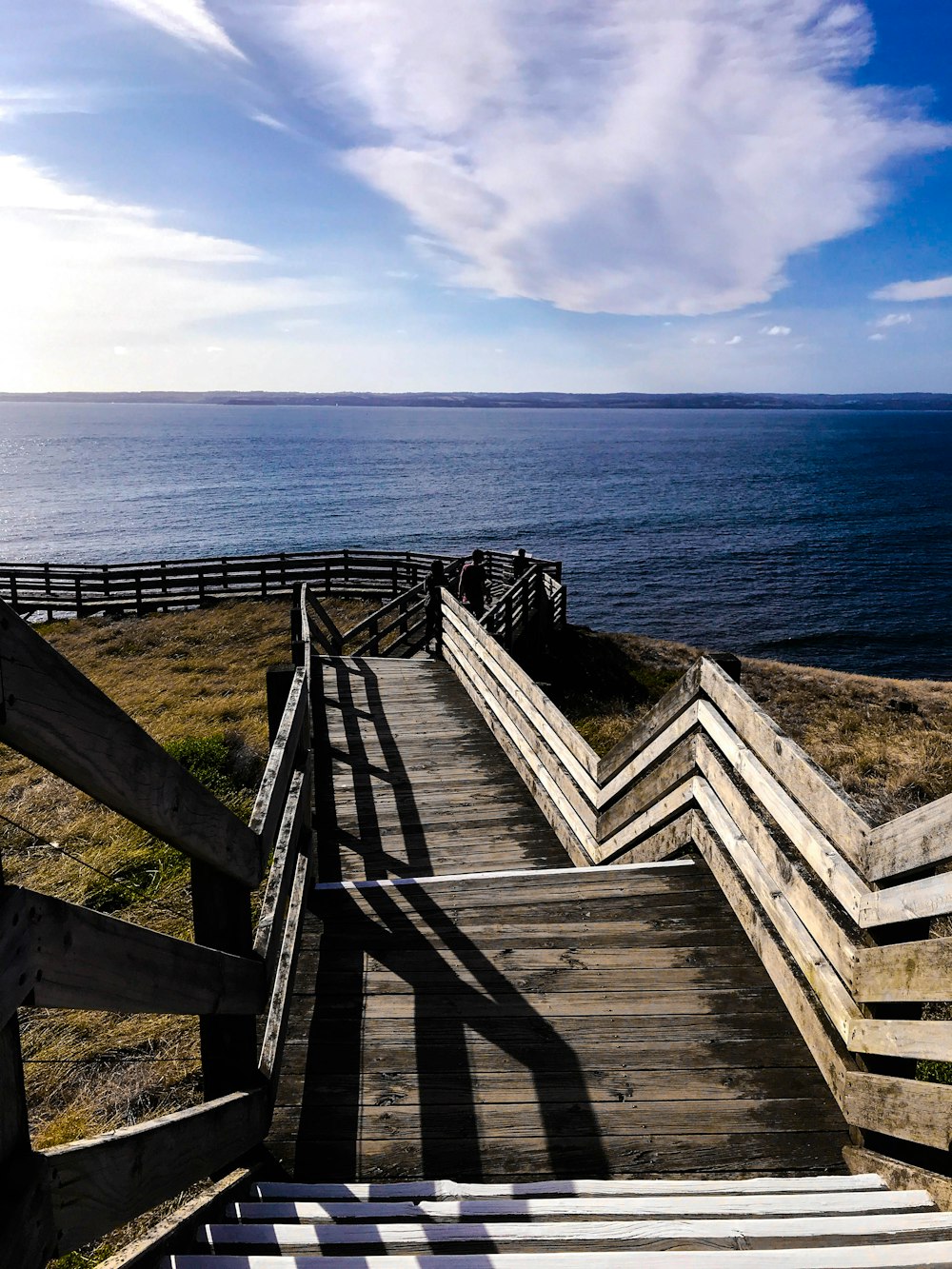 brown wooden fence on brown wooden dock near blue sea under blue sky during daytime