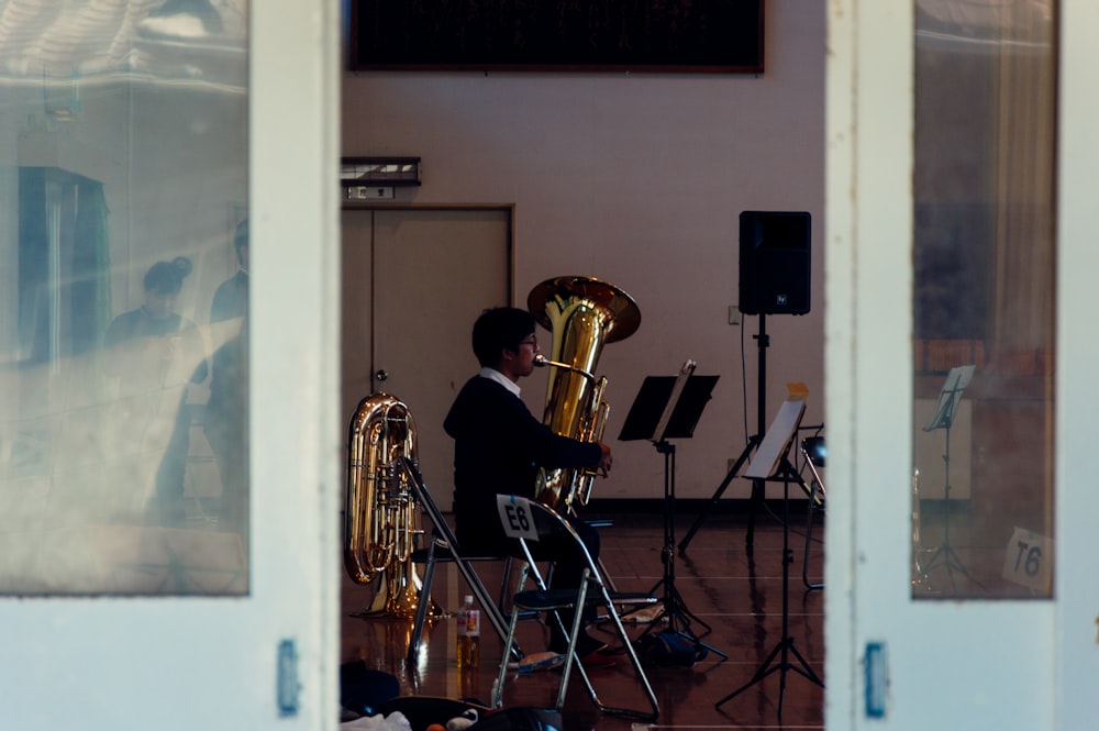 man playing brass trumpet sitting on chair