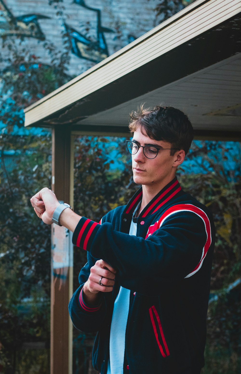 man in black and red jacket wearing black framed eyeglasses