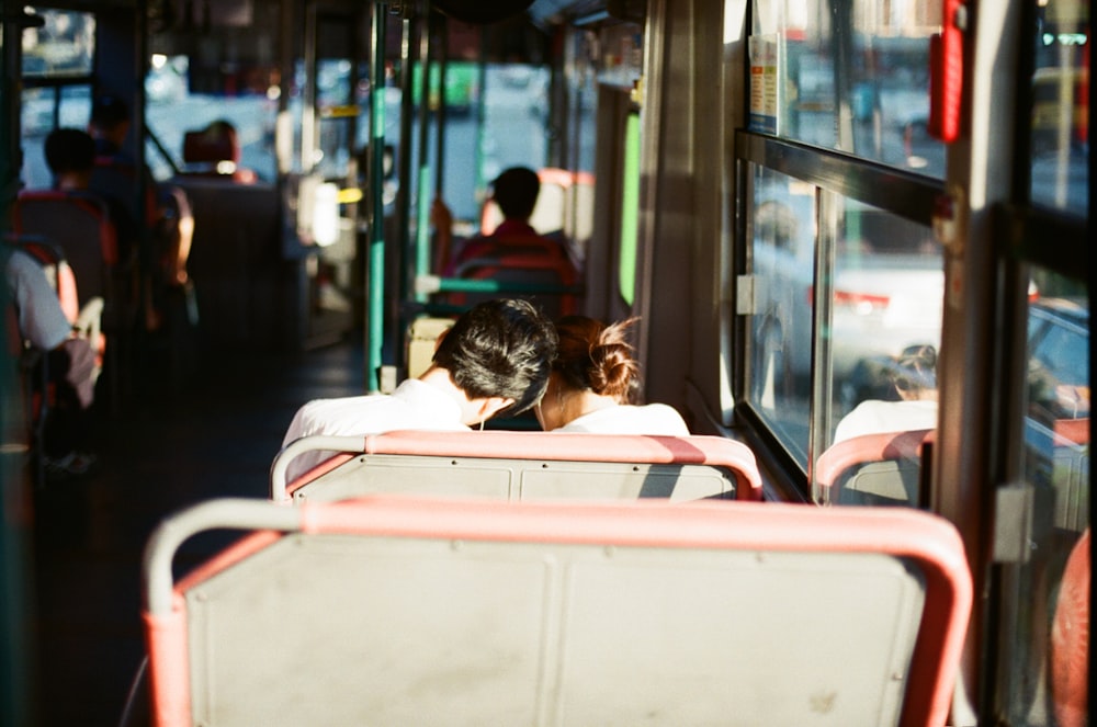 man and woman sitting on white and red bus