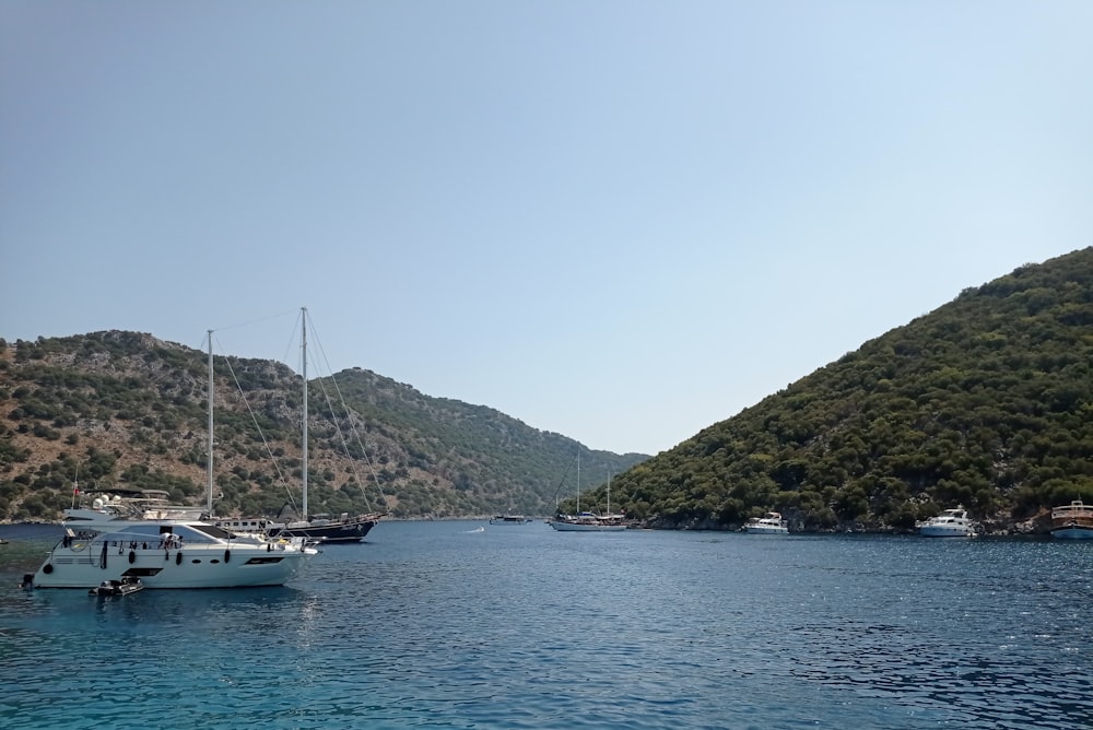 white boat on body of water near mountain during daytime