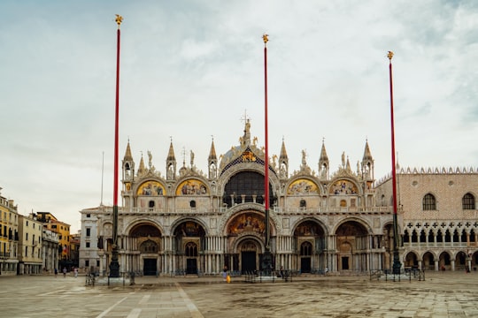 brown and white concrete building under white clouds during daytime in Saint Mark's Basilica Italy