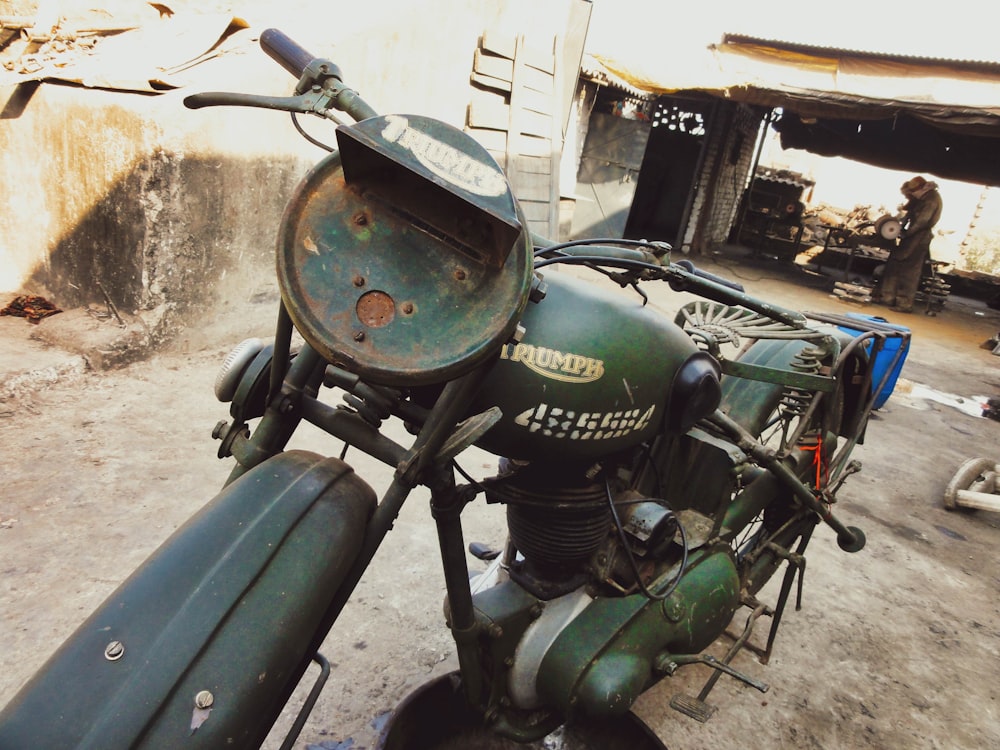 green and black motorcycle parked beside white wall