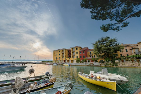 People riding on boat on river near buildings during daytime — Lake Garda, Italy