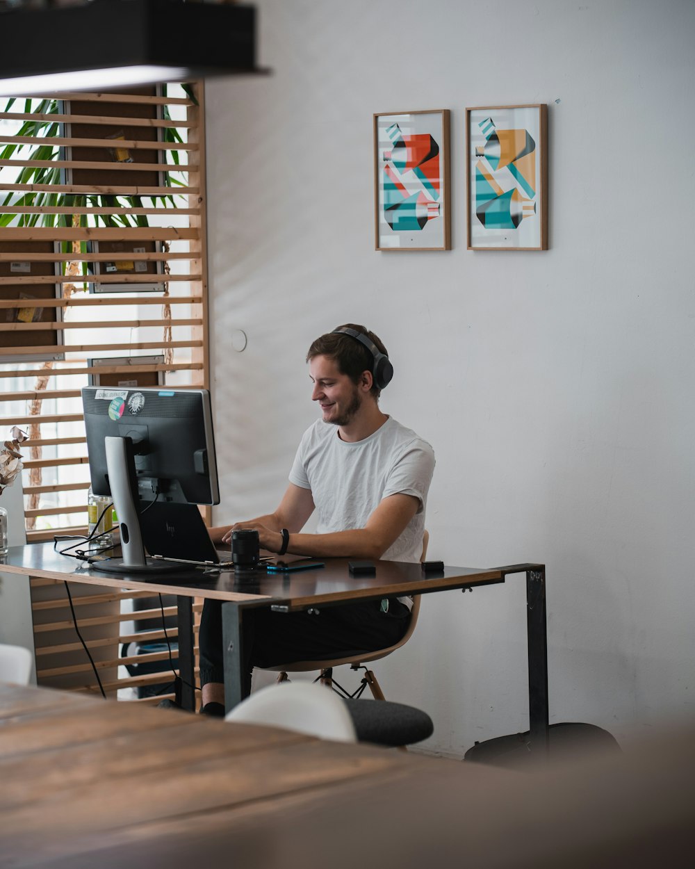 Hombre con camiseta blanca de cuello redondo sentado en una silla negra de oficina