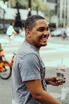 A smiling customer holding a custom cup with the pacibrail logo.