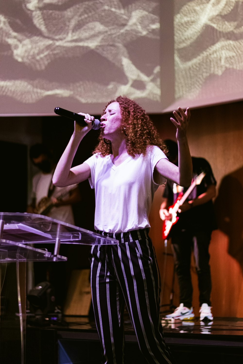 woman in white shirt singing on stage