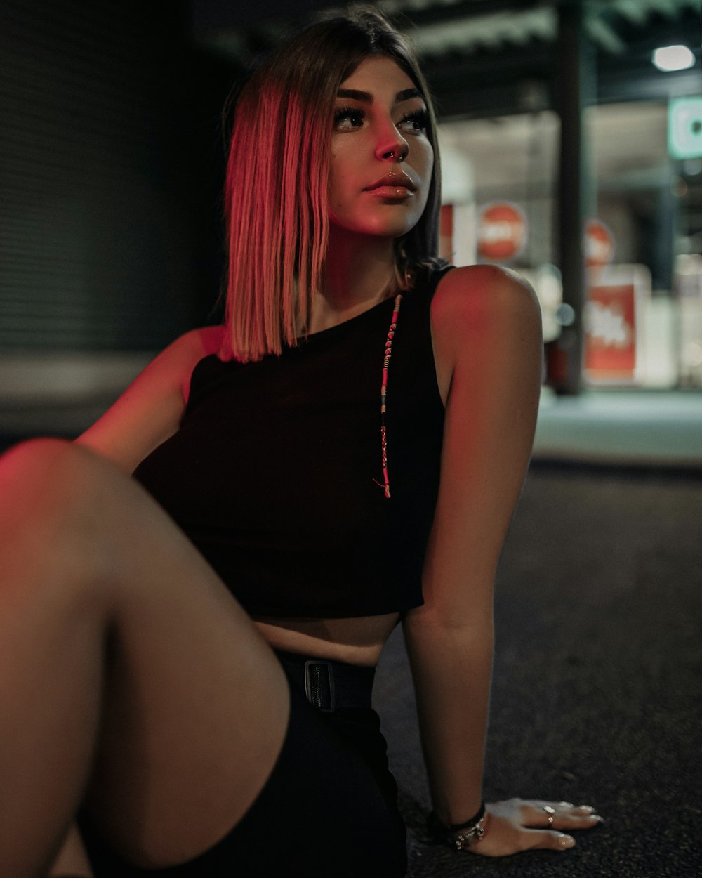 woman in black tank top and black shorts sitting on gray concrete floor