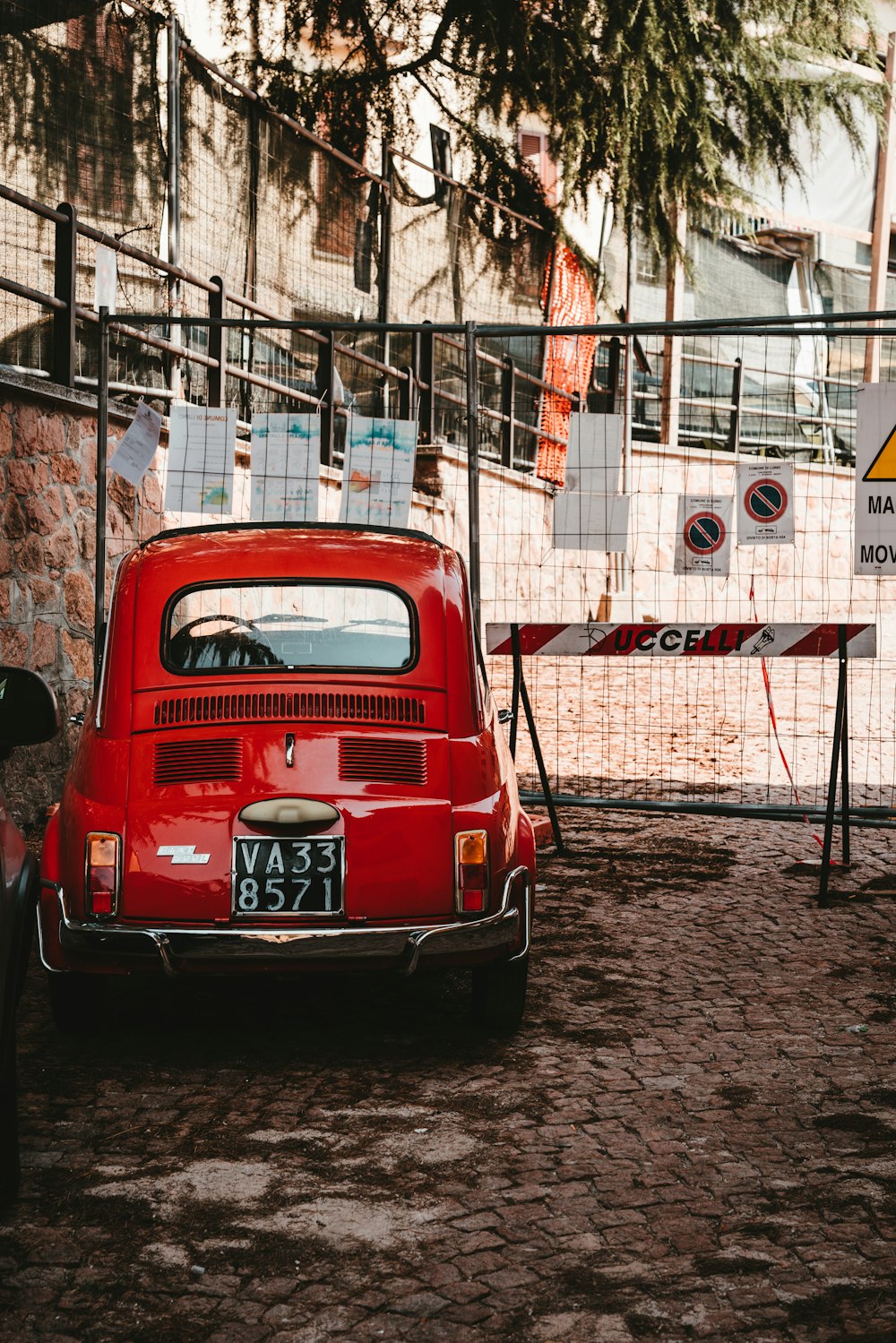 red car parked beside gray metal fence