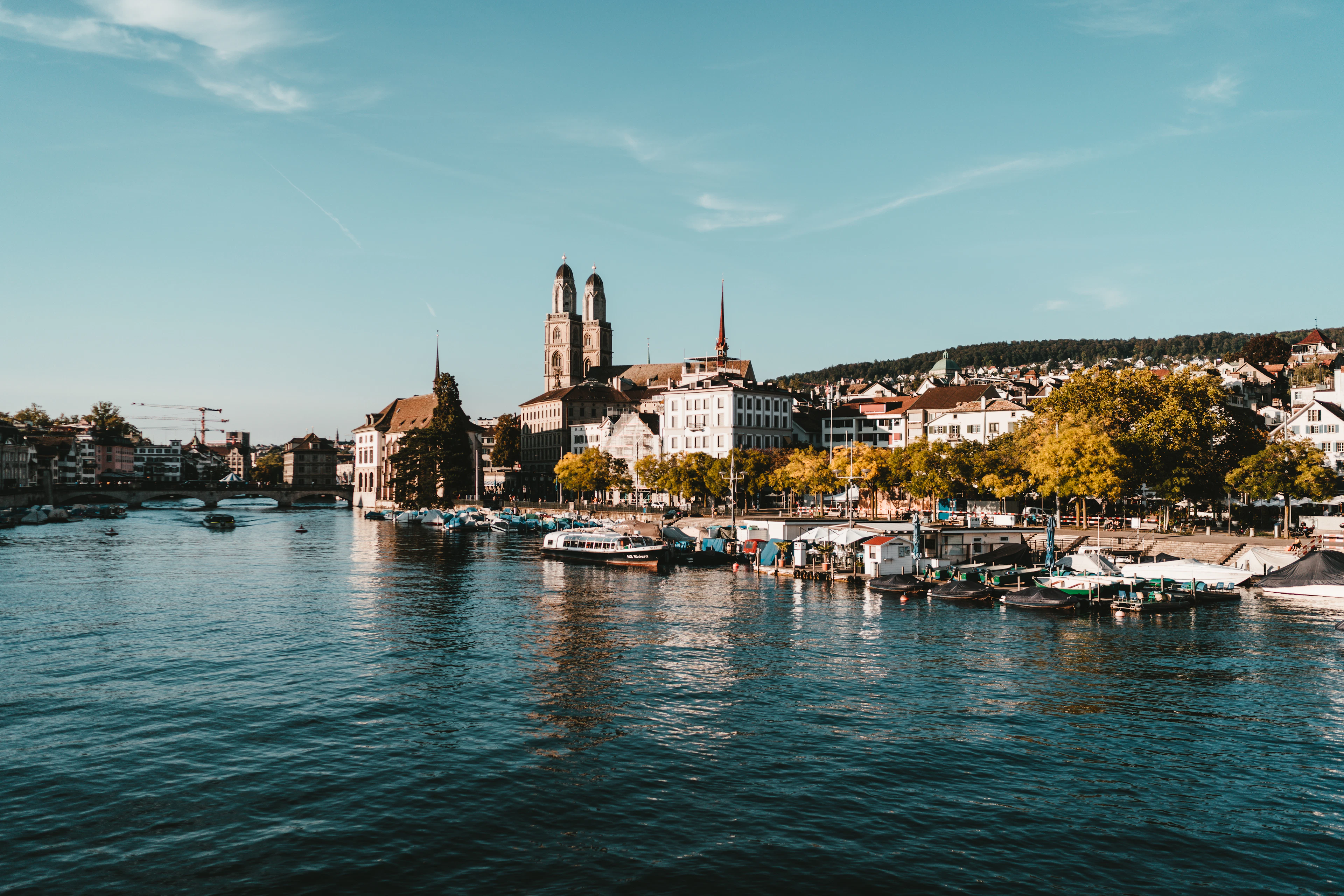 Boats moored along the quay where the Limmat meets Lake Zurich, below the twin towers of the Grossmuenster.
