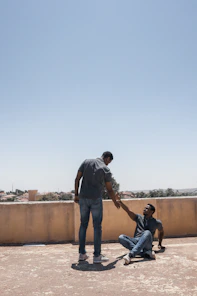 man in gray t-shirt and blue denim jeans standing beside man in black t-shirt
