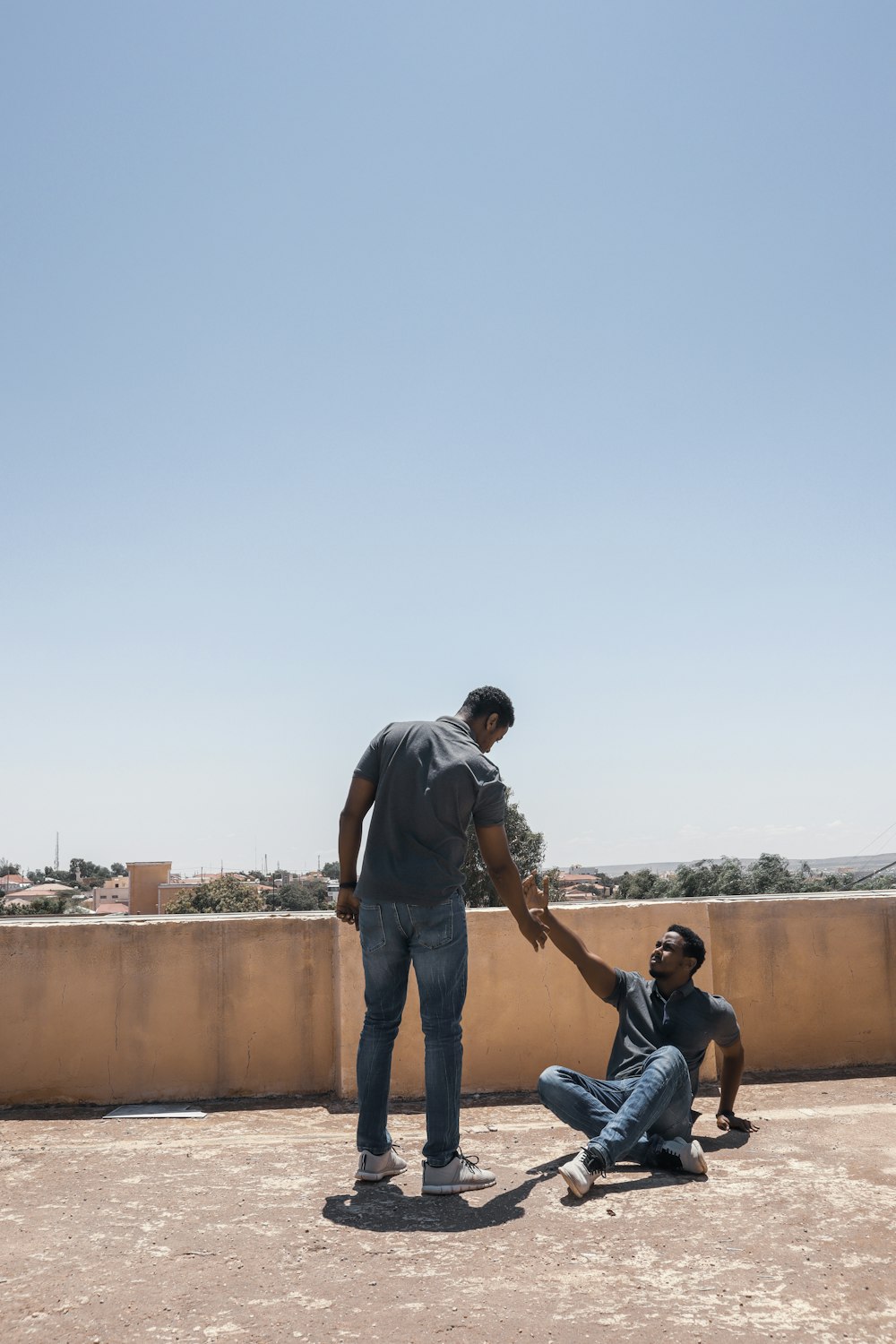 man in gray t-shirt and blue denim jeans standing beside man in black t-shirt