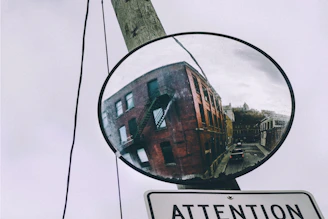 A safety worker installing a reflective convex mirror beside a warehouse loading dock.