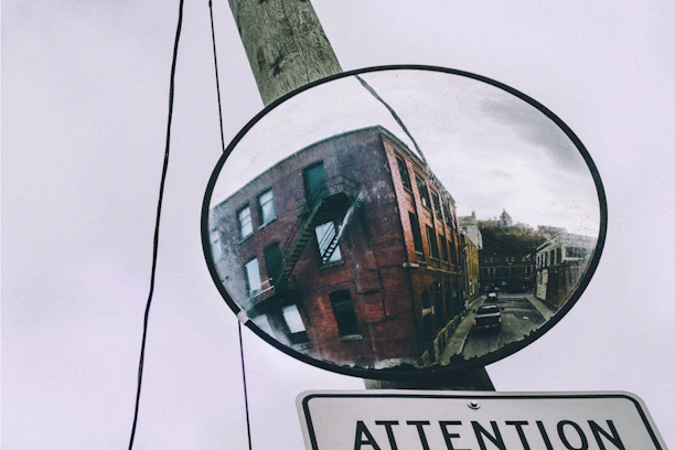 A safety worker installing a reflective convex mirror beside a warehouse loading dock.