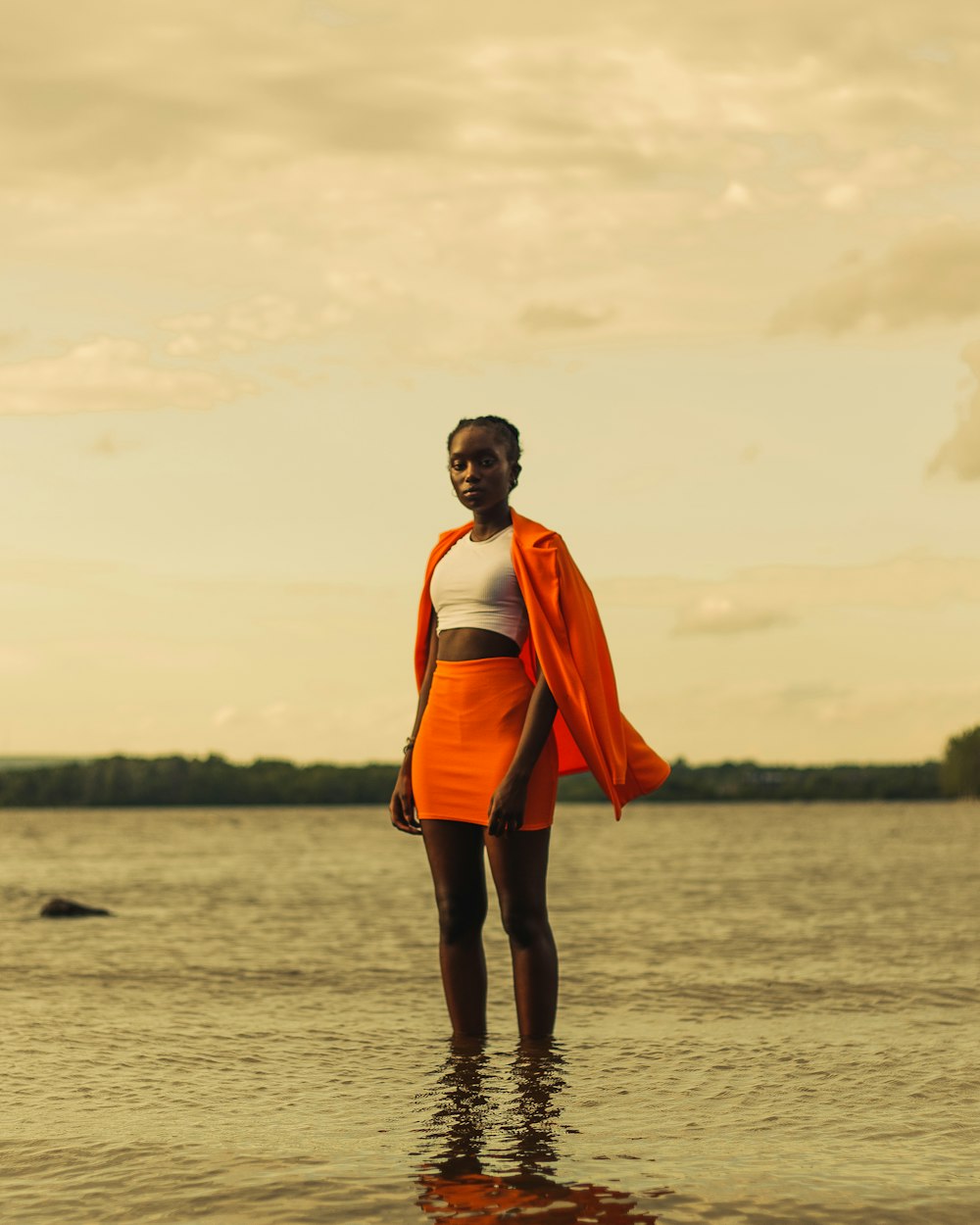 Mujer en chaqueta naranja de pie sobre el agua durante el día