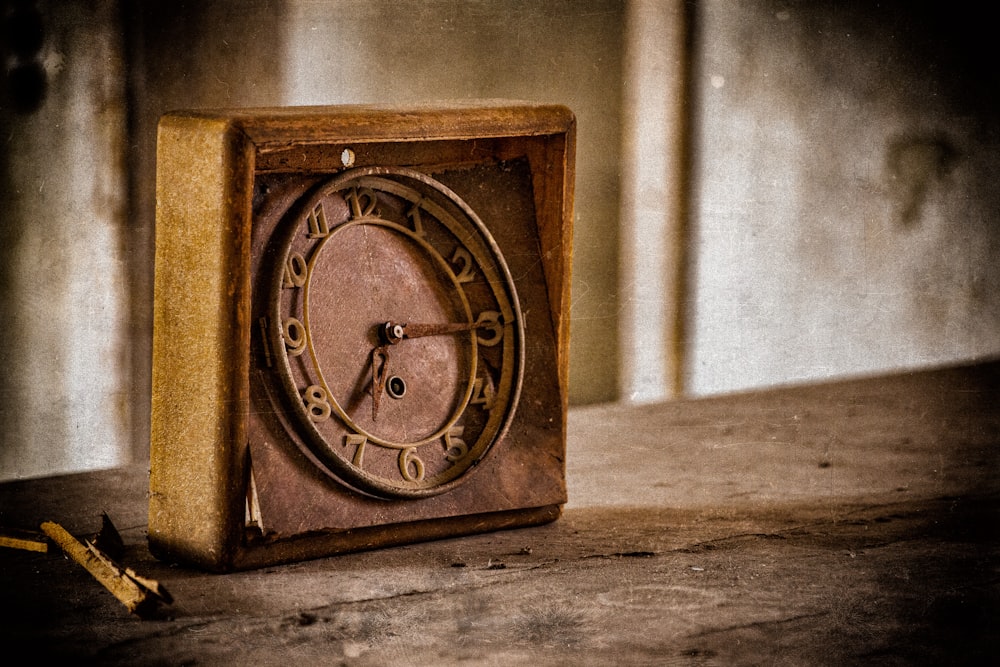 Reloj analógico de madera marrón sobre mesa de madera marrón