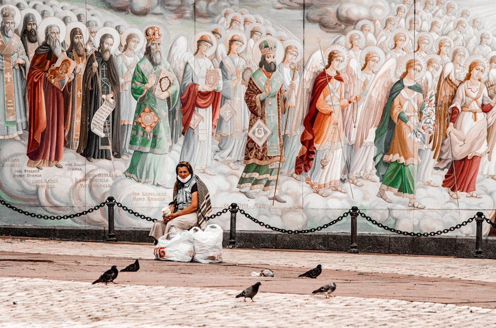 people in white and brown traditional dress sitting on black metal bench