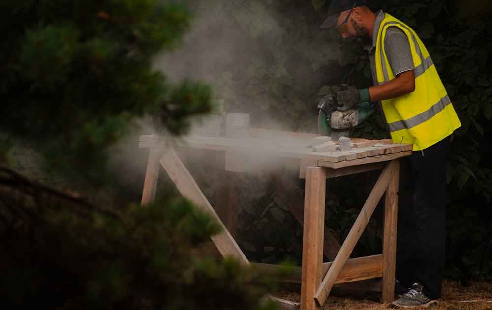 man in yellow and black jacket standing on brown wooden ladder