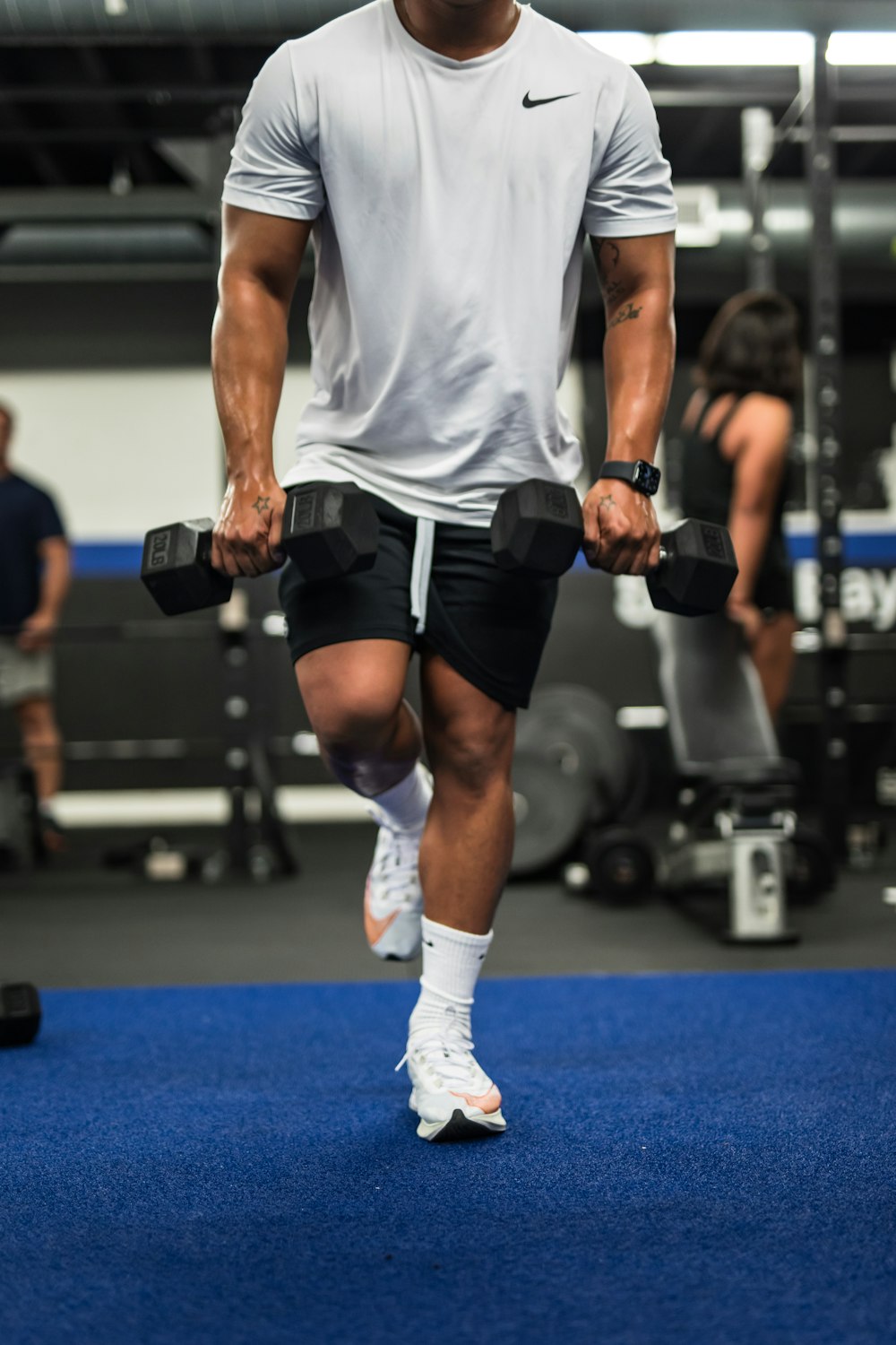 man in gray tank top and black shorts holding black dumbbell