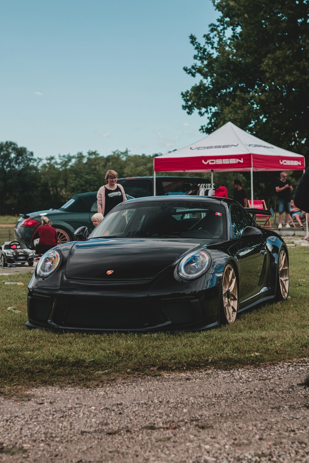 black porsche 911 parked on green grass field during daytime