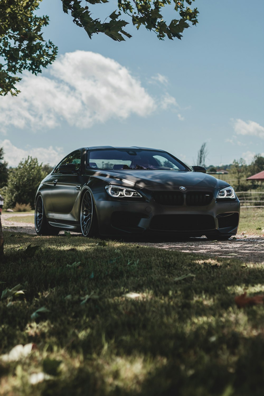 black bmw m 3 coupe on green grass field under white clouds and blue sky during