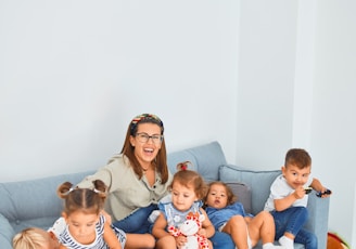 woman sitting on gray couch with 5 children