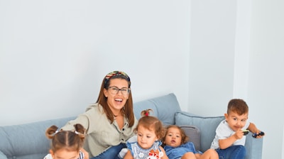woman sitting on gray couch with 5 children