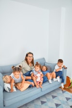 woman sitting on gray couch with 5 children