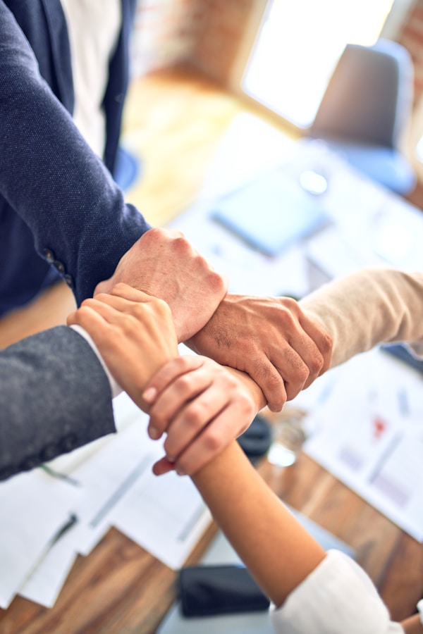 Group of business workers standing with hands together doing symbol at the officeby krakenimages