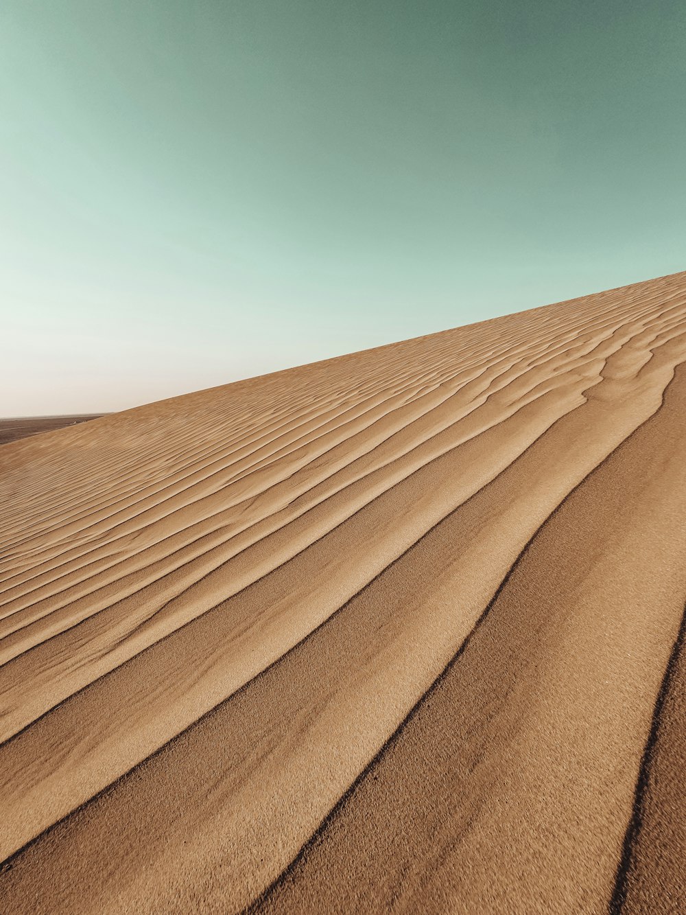 sable brun sous ciel bleu pendant la journée