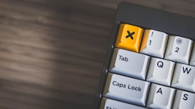 Parte de um teclado com teclas na cor branco e a tecla que representa a letra x na cor amarelo