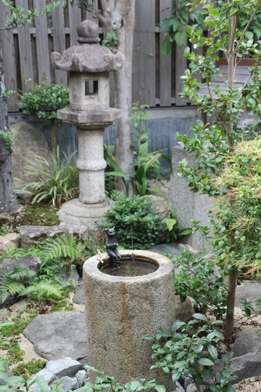 gray concrete outdoor fountain surrounded by green plants